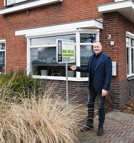 Makelaar plaatst te koop bord bij een woning in Assen