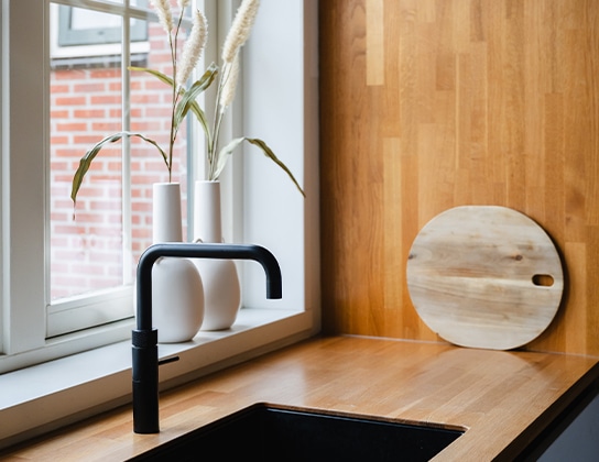 Moderne keuken met houten werkblad en zwarte kraan bij raam
