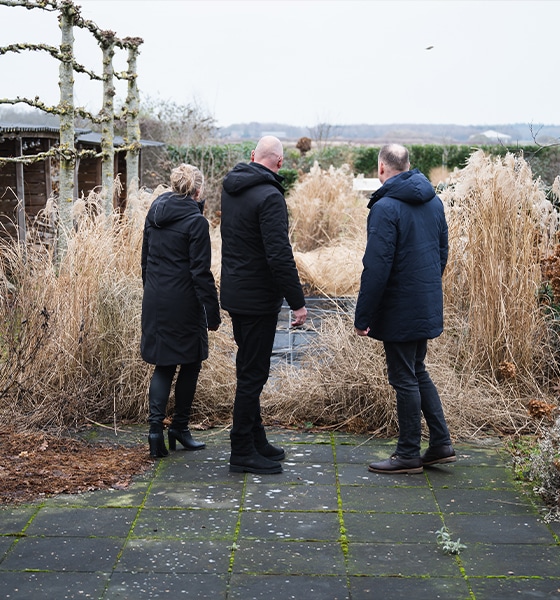 Makelaar beoordeelt samen met klanten de tuin en het perceel van een woning