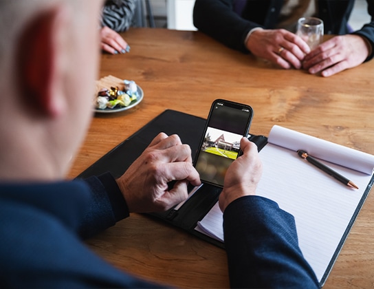 Makelaar bespreekt woningpresentatie met klanten aan tafel in Assen